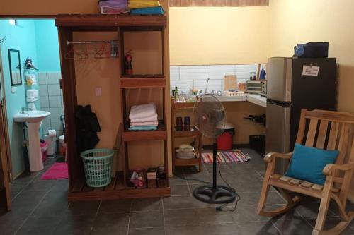 Habitación con cocina con nevera y ventilador de suelo. en Casita Olivia, en Sámara