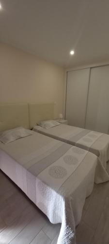 two beds in a room with white walls at Rocha Apartment 1016 in Portimão