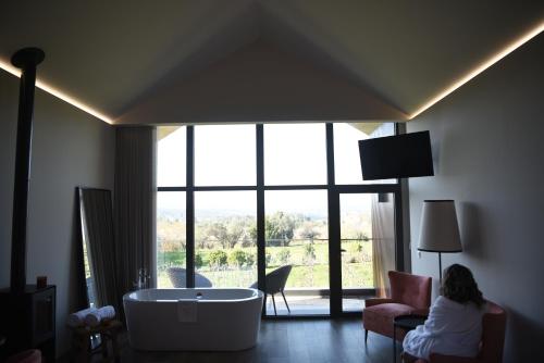 a woman sitting in a room with a tub in front of a window at Casa Valxisto in Penafiel