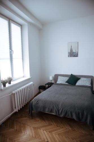 a white bedroom with a bed and two windows at Room in Old Town Krakow in Kraków