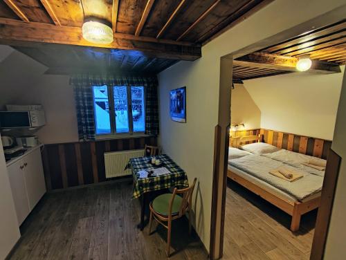 a small bedroom with a bed and a table at Penzion Pod můstky in Harrachov