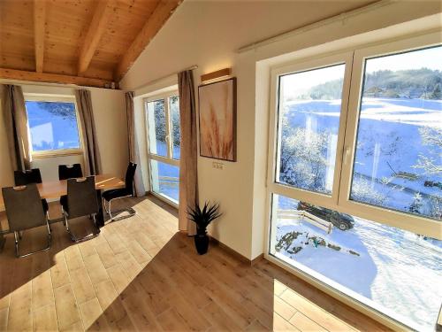 uma sala de estar com uma mesa e duas janelas grandes em Landhaus am Schindelberglift em Oberstaufen