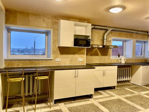 una cocina con armarios blancos y una barra con taburetes en Riverside Motel Jelgava en Jelgava