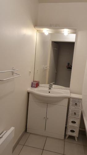La salle de bains blanche est pourvue d'un lavabo et d'un miroir. dans l'établissement l'hippocampe, à Cayeux-sur-Mer