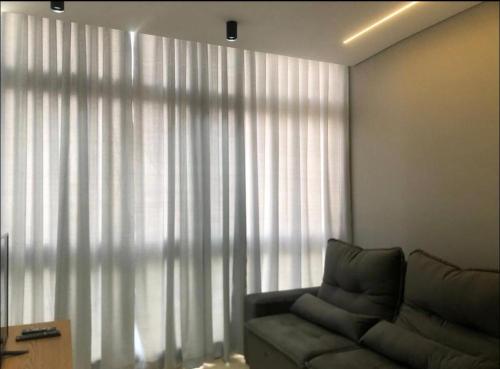 a living room with a couch and a large window at Diamond é o seu lugar ! in Belo Horizonte