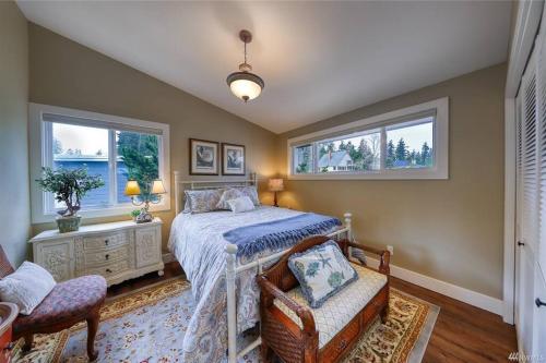 a bedroom with a bed and two chairs and windows at Oasis By The Sea in Port Hadlock