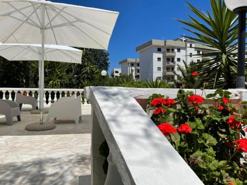 a balcony with red flowers and a white umbrella at Villa Angela Suite in Taranto