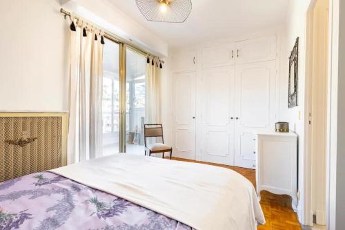 biała sypialnia z łóżkiem i oknem w obiekcie Eat - Sleep - Wander Chic and Cosy Flat w Nicei