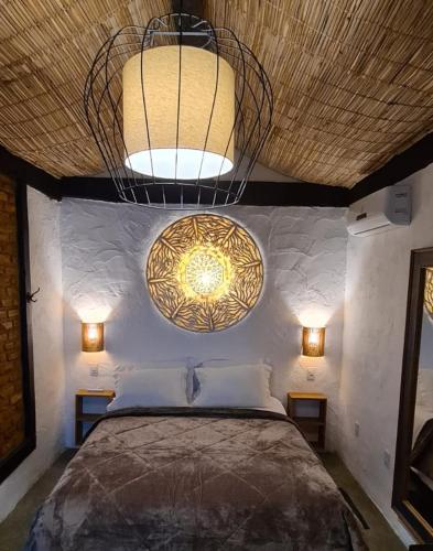1 dormitorio con cama y lámpara de araña en Pouso Araris - Araras, Vale das Videiras en Petrópolis