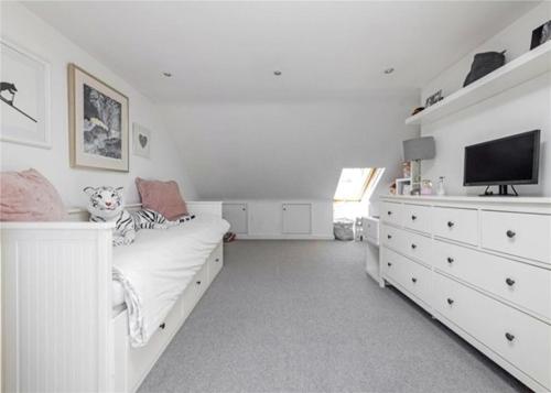 a white bedroom with a bed and a flat screen tv at Battersea boutique townhouse in London