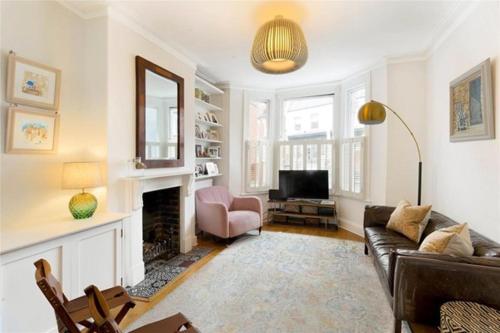 ein Wohnzimmer mit einem Sofa und einem Kamin in der Unterkunft Battersea boutique townhouse in London