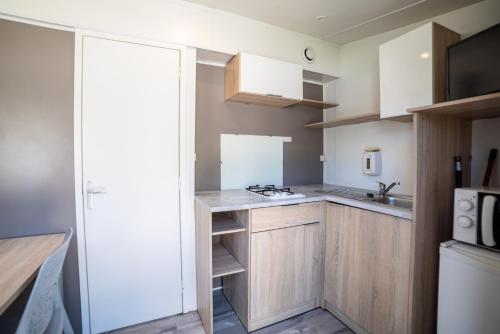 a small kitchen with white cabinets and a sink at Camping du Sevron in Saint-Étienne-du-Bois