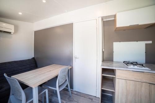 a small kitchen with a wooden table and chairs at Camping du Sevron in Saint-Étienne-du-Bois