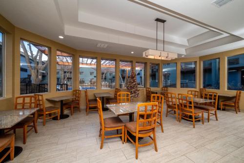um restaurante com mesas, cadeiras e janelas em Endeavor Inn & Suites, Trademark Collection by Wyndham em Topeka
