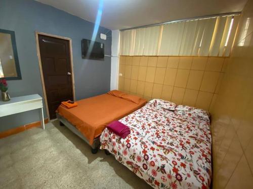 a small bedroom with a bed with an orange blanket at Dpto en Grazota Norte de Guayaquil in Guayaquil