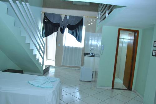 a room with a staircase and a kitchen with a white table at Hotel Industrial Contagem in Contagem