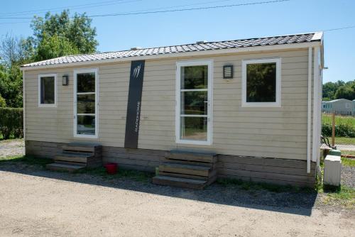 a small white house with steps in front of it at Camping du Sevron in Saint-Étienne-du-Bois