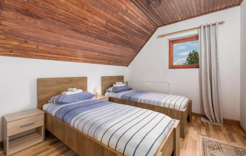 two beds in a room with a wooden ceiling at Angel Holiday House in Ravna Gora