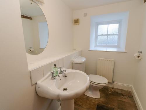 W łazience znajduje się umywalka, toaleta i lustro. w obiekcie East Farm House w mieście Humshaugh