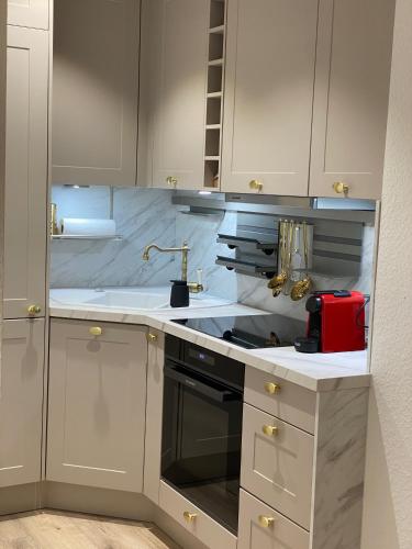 a kitchen with white cabinets and a red appliance at Modernes Apartment an Timmendorfer Promenade, 1. Reihe in Timmendorfer Strand