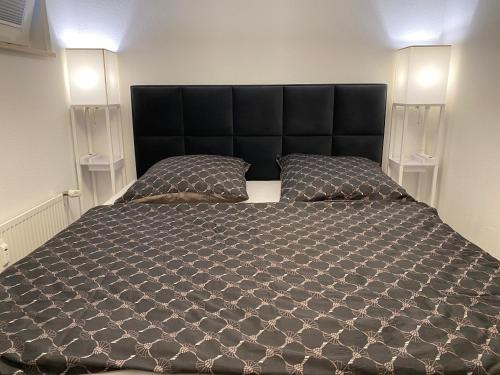 a bedroom with a large black bed with two pillows at Modernes Apartment an Timmendorfer Promenade, 1. Reihe in Timmendorfer Strand