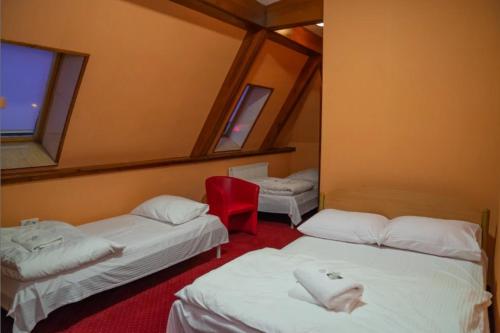 um quarto com três camas e uma cadeira vermelha em Motel Delfin ** em Trojanów
