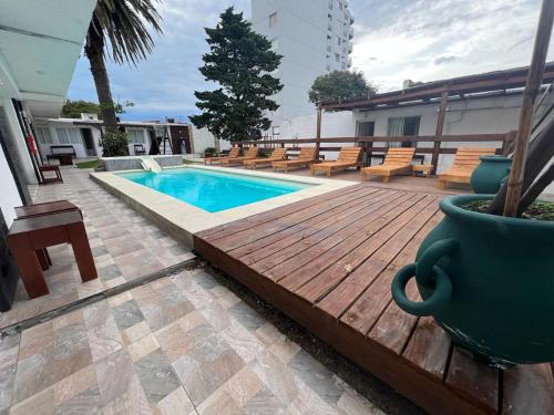 a pool with a wooden deck next to a building at Gran Colonial Riviera in Piriápolis