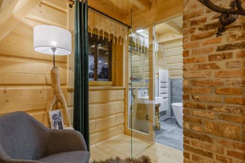 a glass shower in a wooden room with a chair at Domek Na Przełęczy wood house & mountain view in Murzasichle