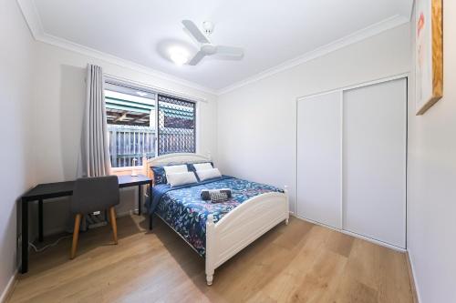 Schlafzimmer mit einem Bett, einem Schreibtisch und einem Fenster in der Unterkunft Redcliffe in Redcliffe