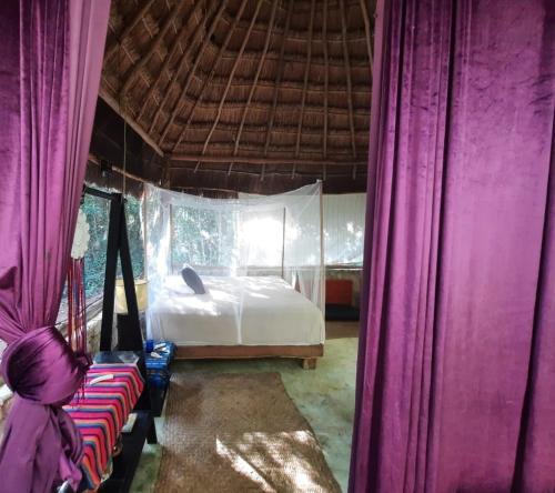 a bedroom with purple curtains and a bed in a room at Toto Aiko in Tulum