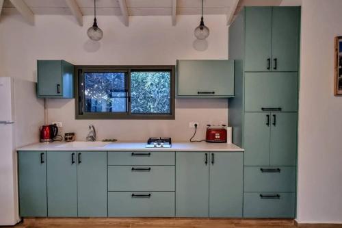 a kitchen with green cabinets and a window at השיטה 5 in Rosh Pinna