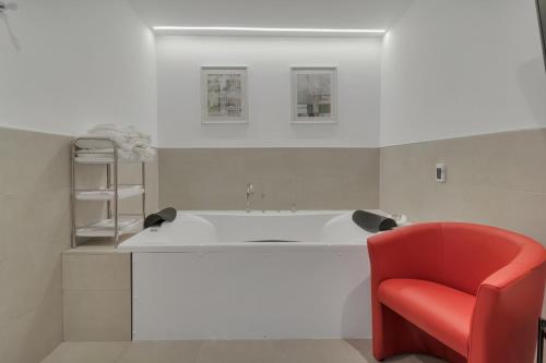 a bathroom with a tub and a red chair at Hotel Ronda Nuevo in Ronda