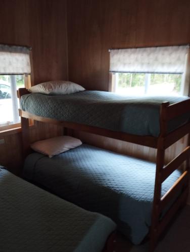 two bunk beds in a room with two windows at Cabañita Sustentable El Este Cochamó in Cochamó