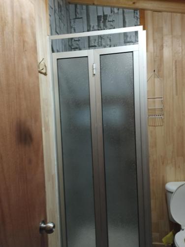 a glass shower door in a bathroom with a toilet at Cabañita Sustentable El Este Cochamó in Cochamó