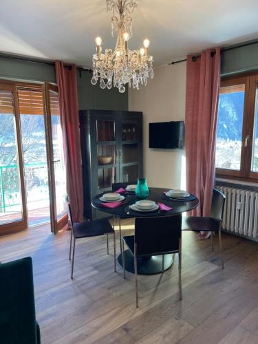 ein Esszimmer mit einem Tisch, Stühlen und einem Kronleuchter in der Unterkunft La Casetta di Bice al Villair di Morgex in Morgex