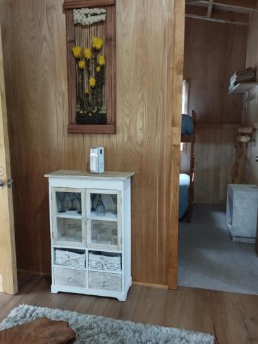 a room with a white cabinet with yellow flowers in a mirror at Cabañita Sustentable El Este Cochamó in Cochamó