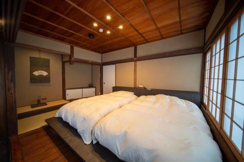 a large white bed in a room with windows at Castle Town Contemporary Ryokan 天籟 - TENRAI - in Takahashi
