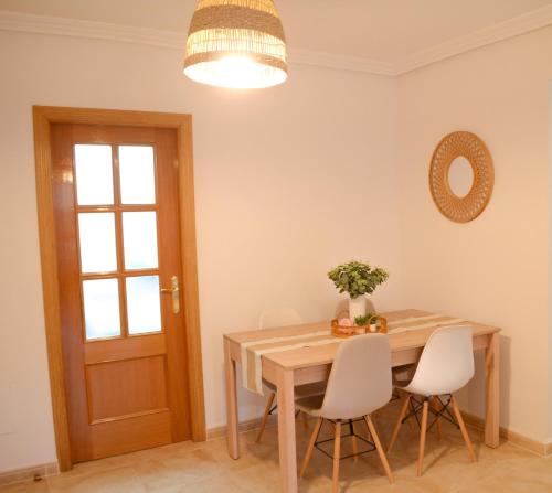 a dining room with a wooden table and white chairs at Dunas de Águilas in Águilas