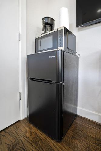 a black refrigerator with a microwave on top of it at Clay Studio in the heart of EADO in Houston