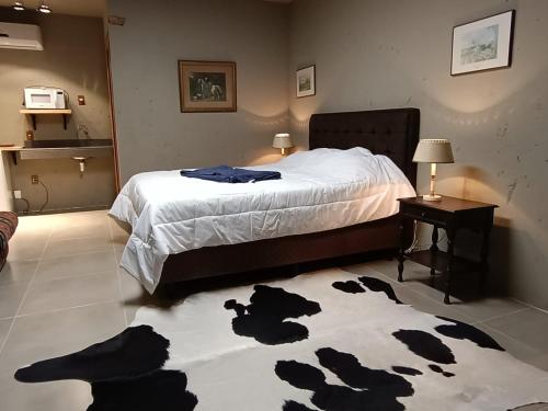 a bedroom with a bed with a cow rug on the floor at Pousada Charqueada Costa do Abolengo in Pelotas