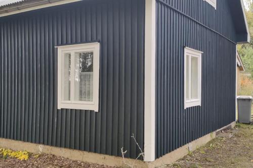uma casa preta com duas janelas do lado em Villa Pikkumustikka em Töysä