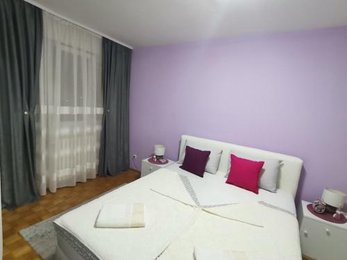 una camera da letto con un letto bianco e cuscini rosa di Sweet Home Gloria a Tuzla