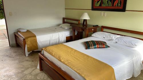 una habitación de hotel con 2 camas y una lámpara en Hotel Tayrona, en Puerto Berrío