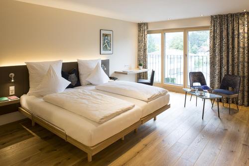 a bedroom with a bed and a desk and a window at Hotel Hoher Freschen in Rankweil