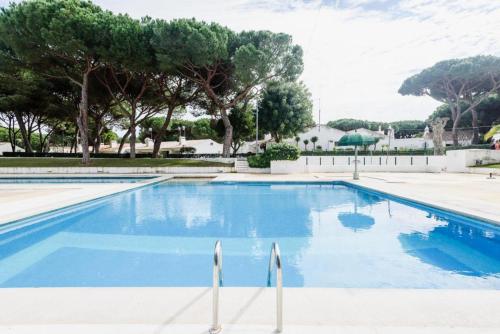a large blue swimming pool with trees in the background at Estúdio na Falésia in Albufeira