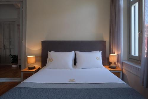a bedroom with a large white bed with two lamps at Eressian Hotel & Hammam Spa in Eresos