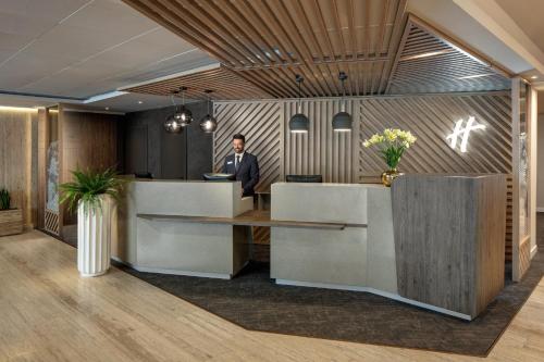 a man in a suit standing at a reception desk at Holiday Inn Rome - Eur Parco Dei Medici, an IHG Hotel in Rome