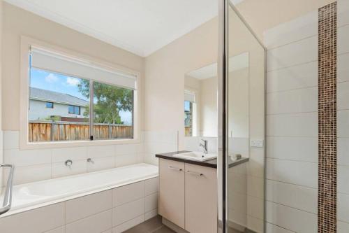 een badkamer met een bad, een wastafel en een douche bij Charming 4 bedrooms house in Truganina /Williams Landing in Laverton