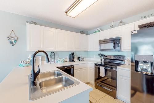 a kitchen with white cabinets and a stainless steel sink at Gulf Island 412 in Navarre