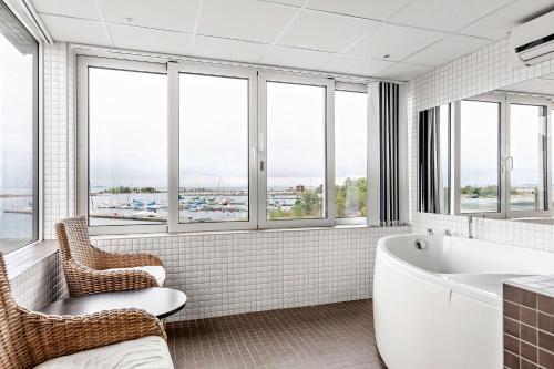 a bathroom with a tub and chairs and windows at Best Western Hotel Corallen in Oskarshamn